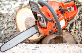 gasoline powered professional chainsaw on pile of cut wood against winter and snow background